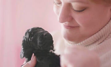 Woman looking lovingly at black puppy