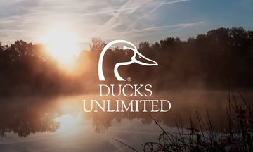 Ducks Unlimited logo placed over a serene lake at sunrise