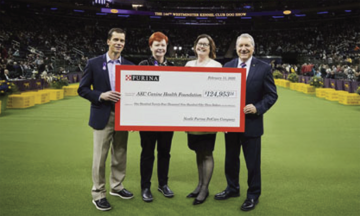 image of four people holding a large donation check at the national dog show