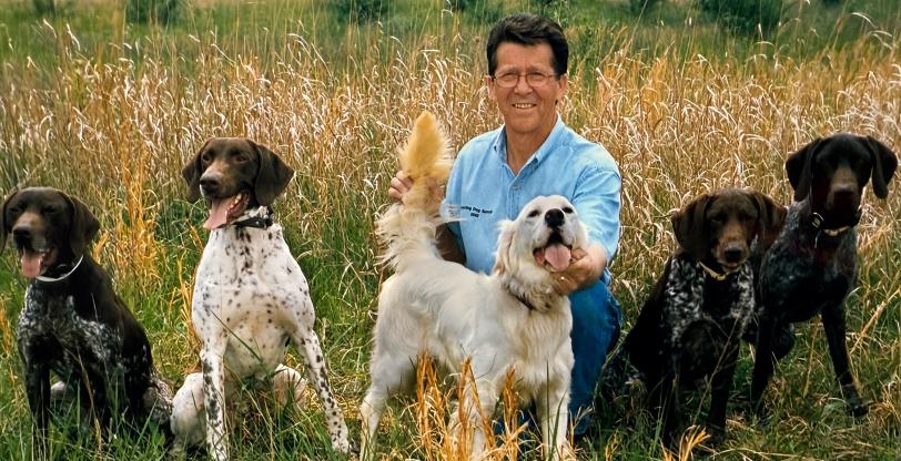 Bob West posing with sport dogs in a field.  