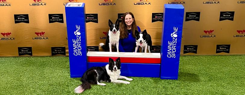 Canine Sports Zone co-owner and director posing with three dogs at North Central Regional Championship.