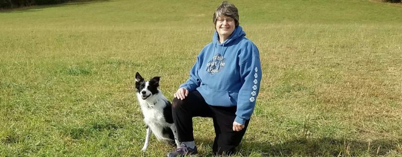 USDAA&#039;s Janet Gauntt posing with a dog in a field.