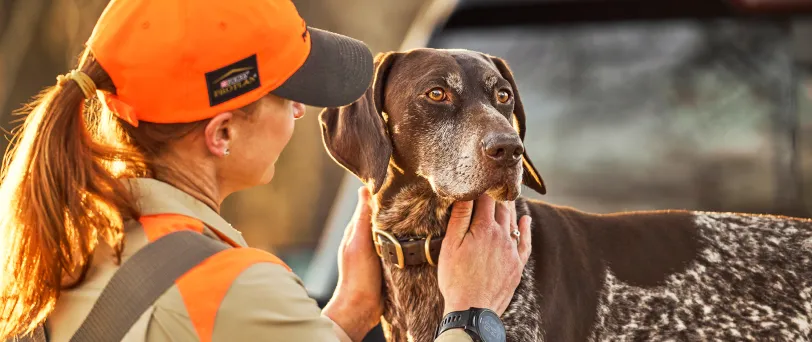 Hunter petting their dog’s neck.