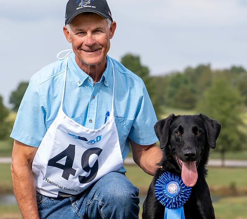 Tommy, also known as Pairadocs' Who's The Wizard, celebrating his achievement as the 2025 National Retriever Derby Champion.
